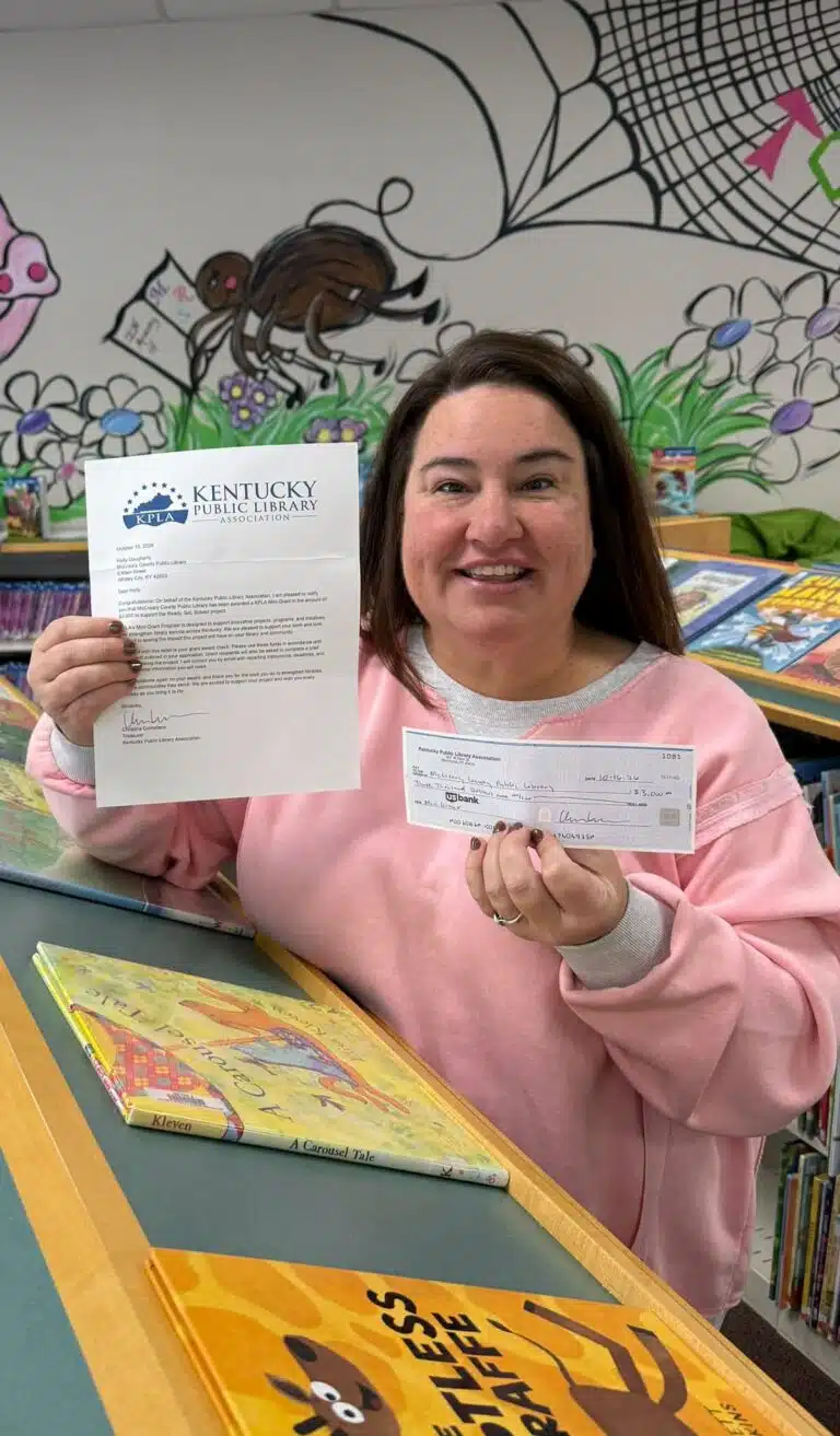 Mrs. Holly holding a grant letter and check for a KDLA Mini Grant