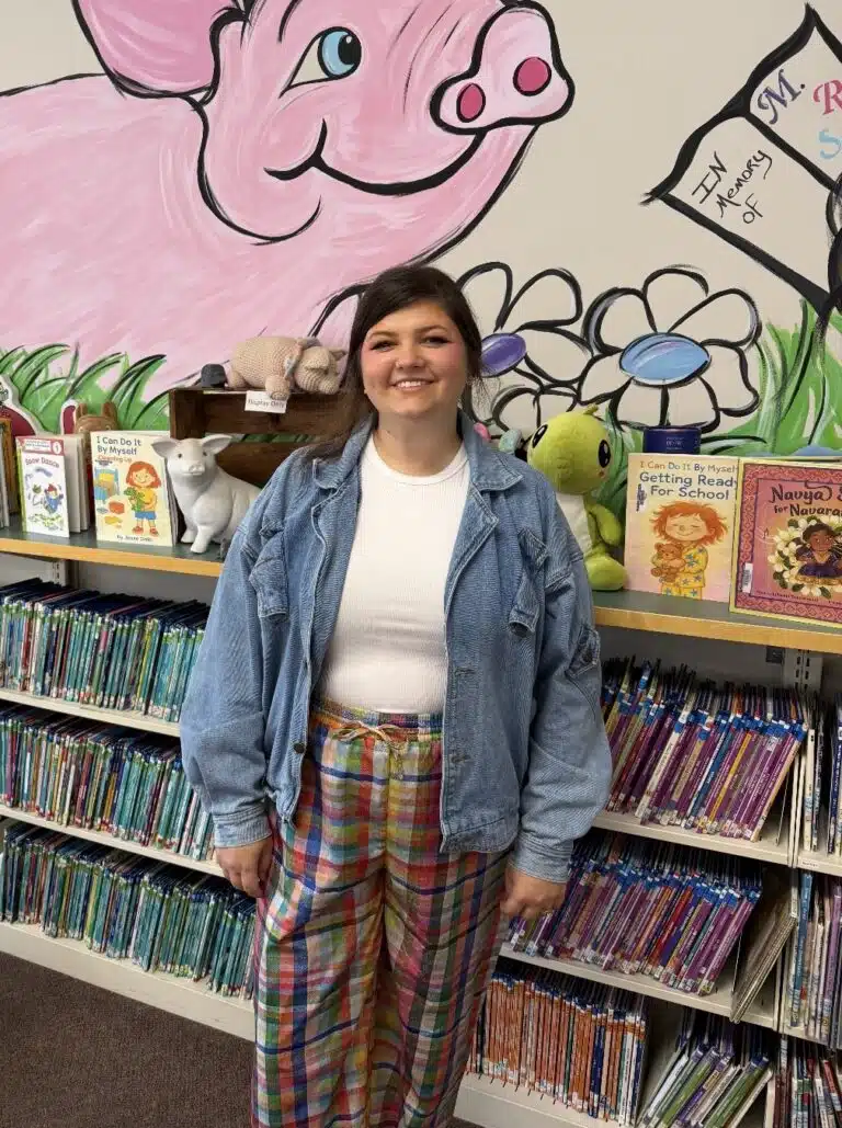 Photo shows a woman (Victoria Smith) standing in the library.